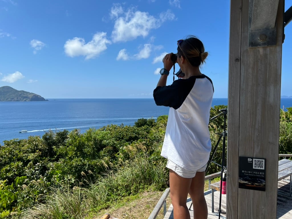 Frau mit Fernglas an der Küste