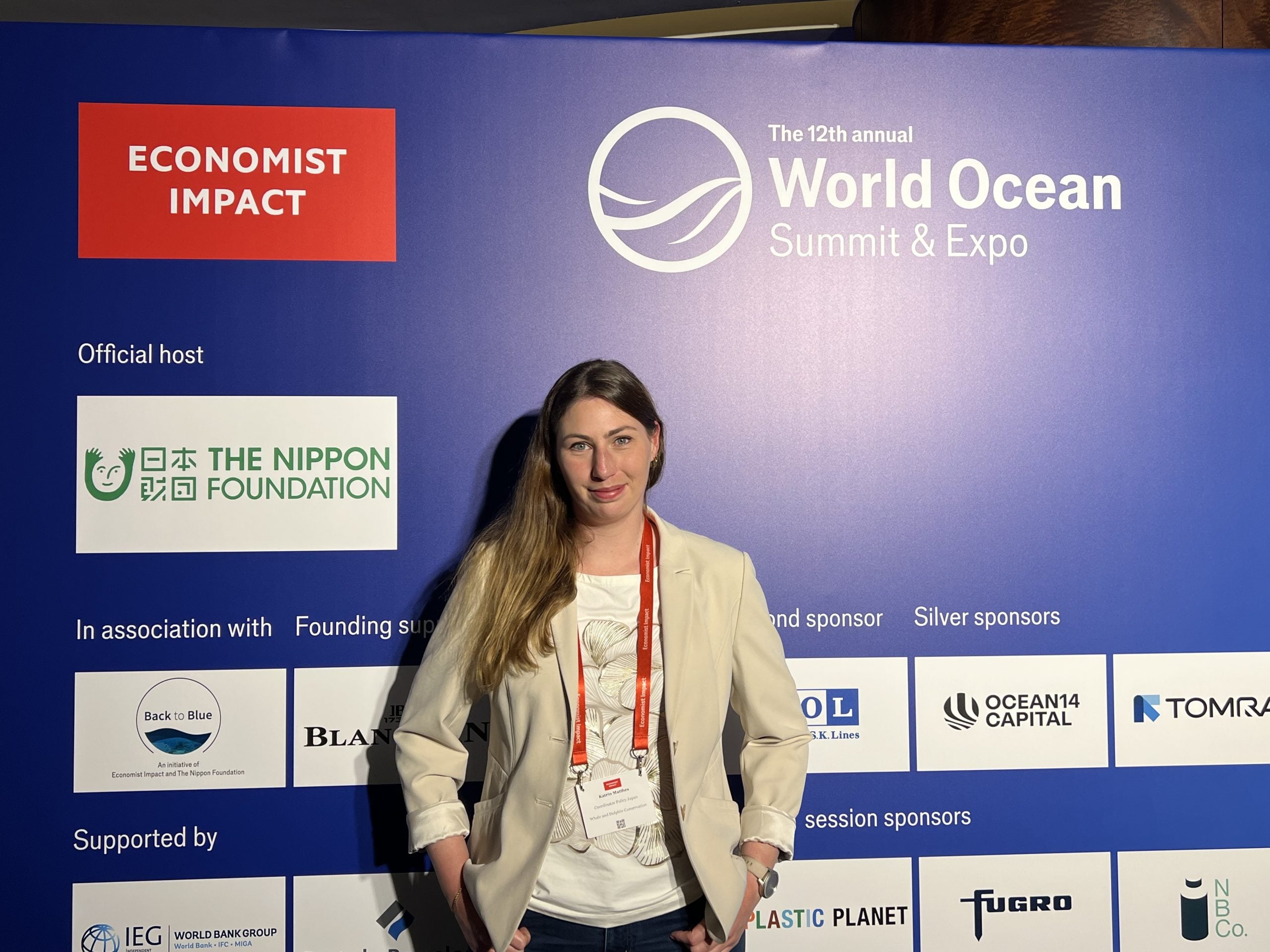 Frau steht vor Sponsorenwand des World Ocean Summit in Tokio, Japan