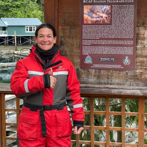 Frau in rotem Overall vor Informationstafel