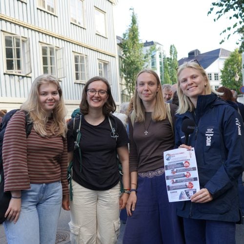 Eine Gruppe junger Menschen hält ein Informationsblatt in einer Fußgängerzone in die Kamera